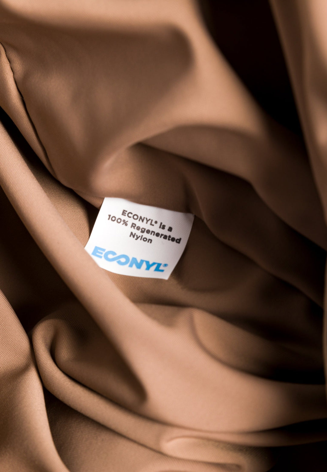 Close-up of brown fabric with an ECONYL is a 100% Regenerated Nylon label