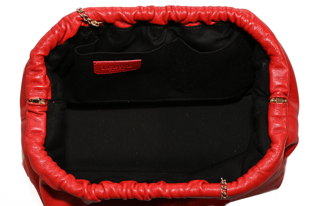 Red leather handbag with black interior and gold chain accents