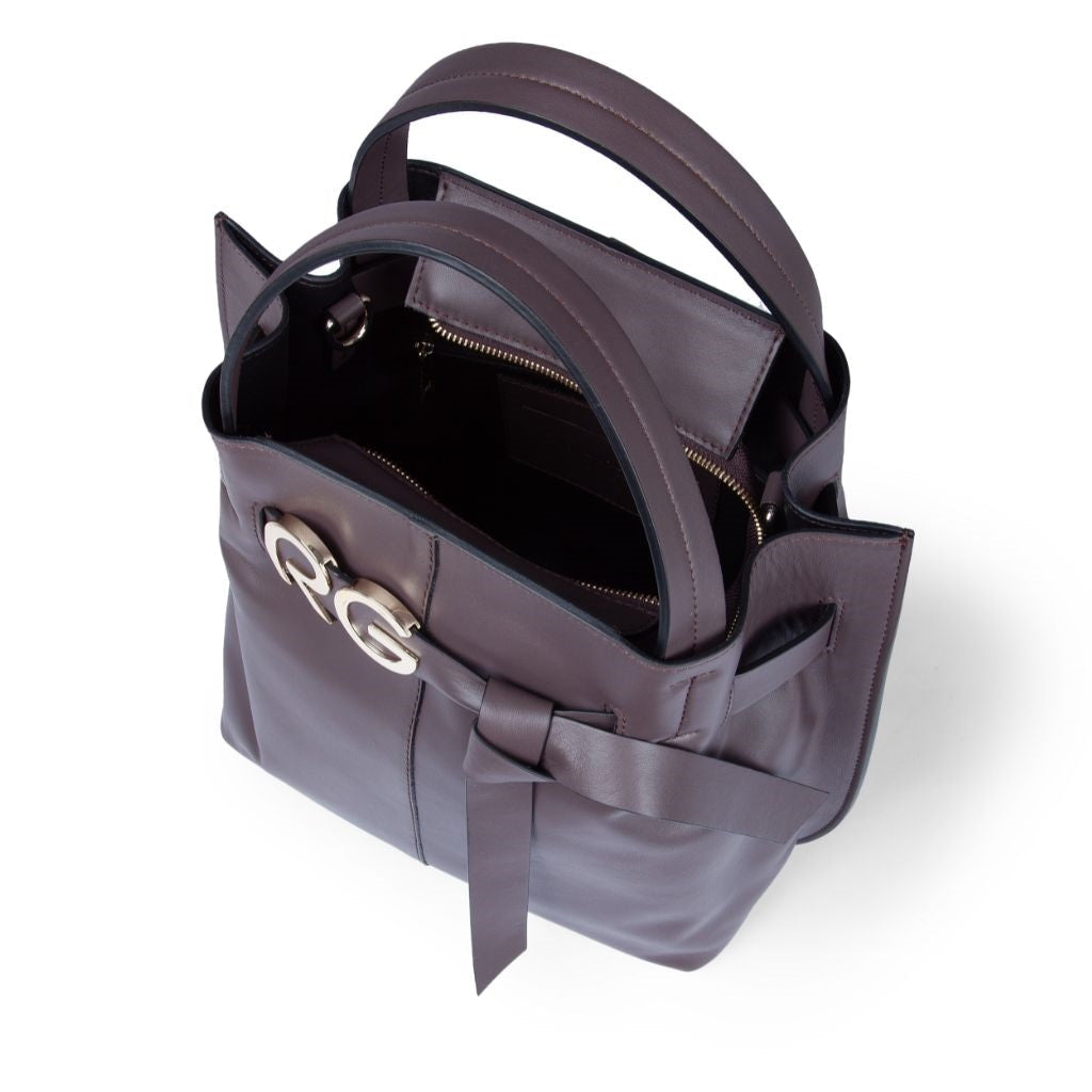 Top view of an open dark purple leather handbag with twin handles and a zippered pocket inside