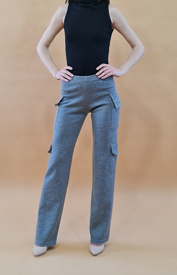 Woman posing in grey cargo pants and black sleeveless top against beige background