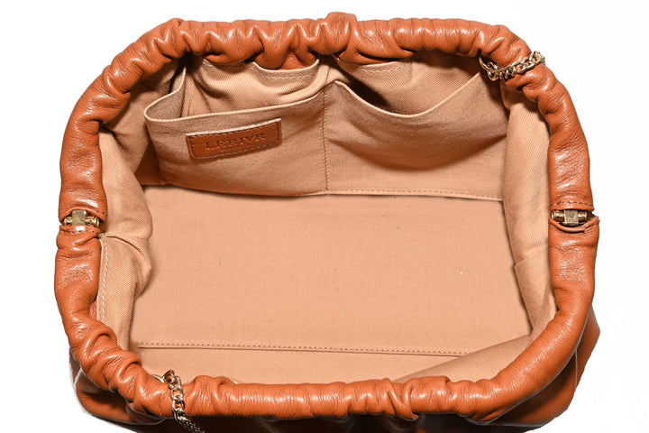 Interior view of an open leather designer handbag with beige fabric lining and multiple pockets