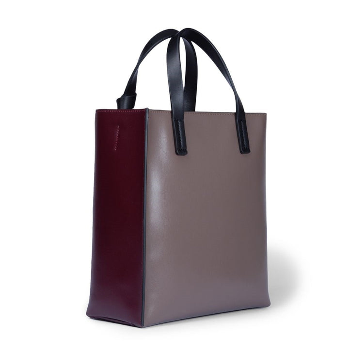 Two-tone leather tote bag with black handles, featuring brown front and maroon side panels