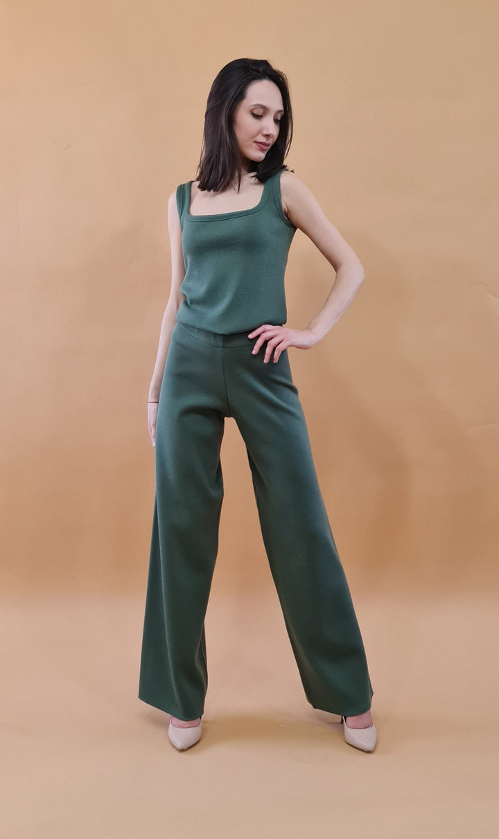 Woman in stylish green two-piece outfit posing against a beige background