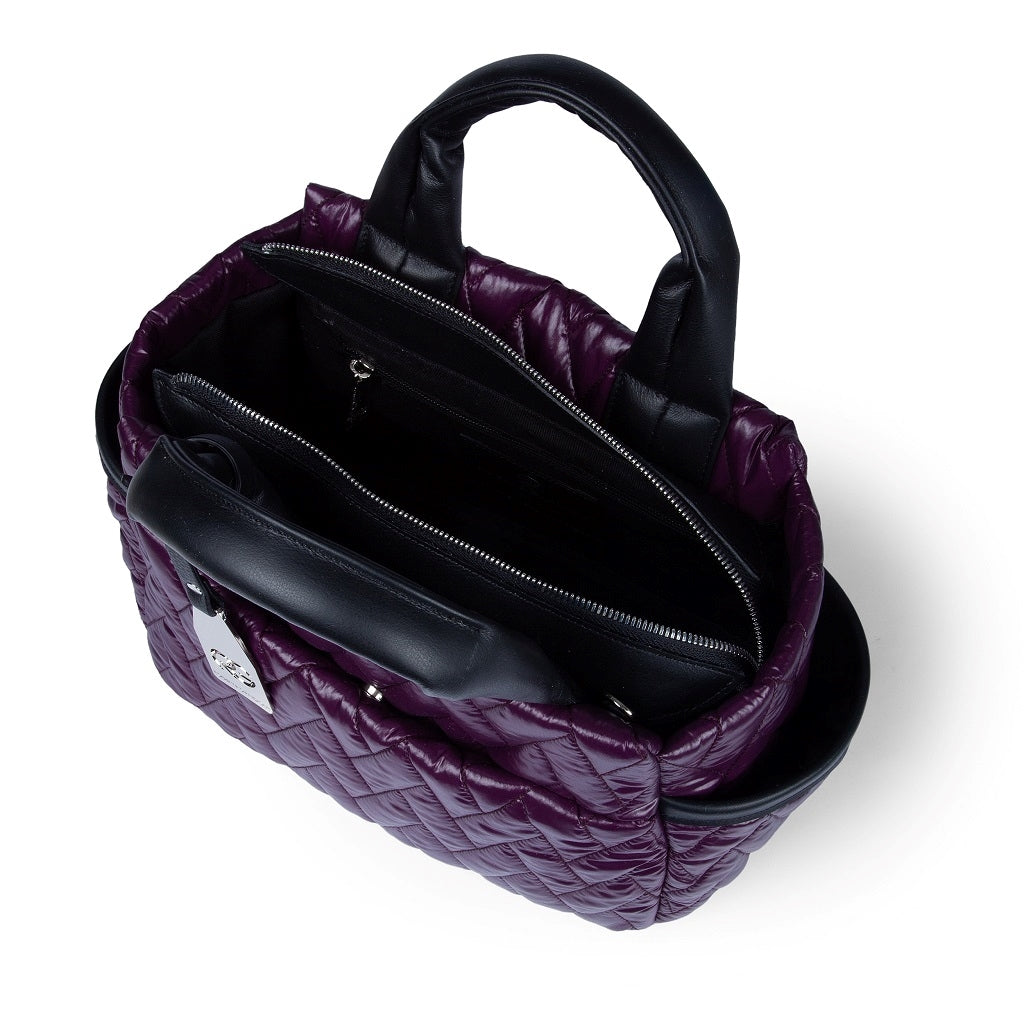 Top view of a stylish purple quilted handbag with black handles and multiple compartments