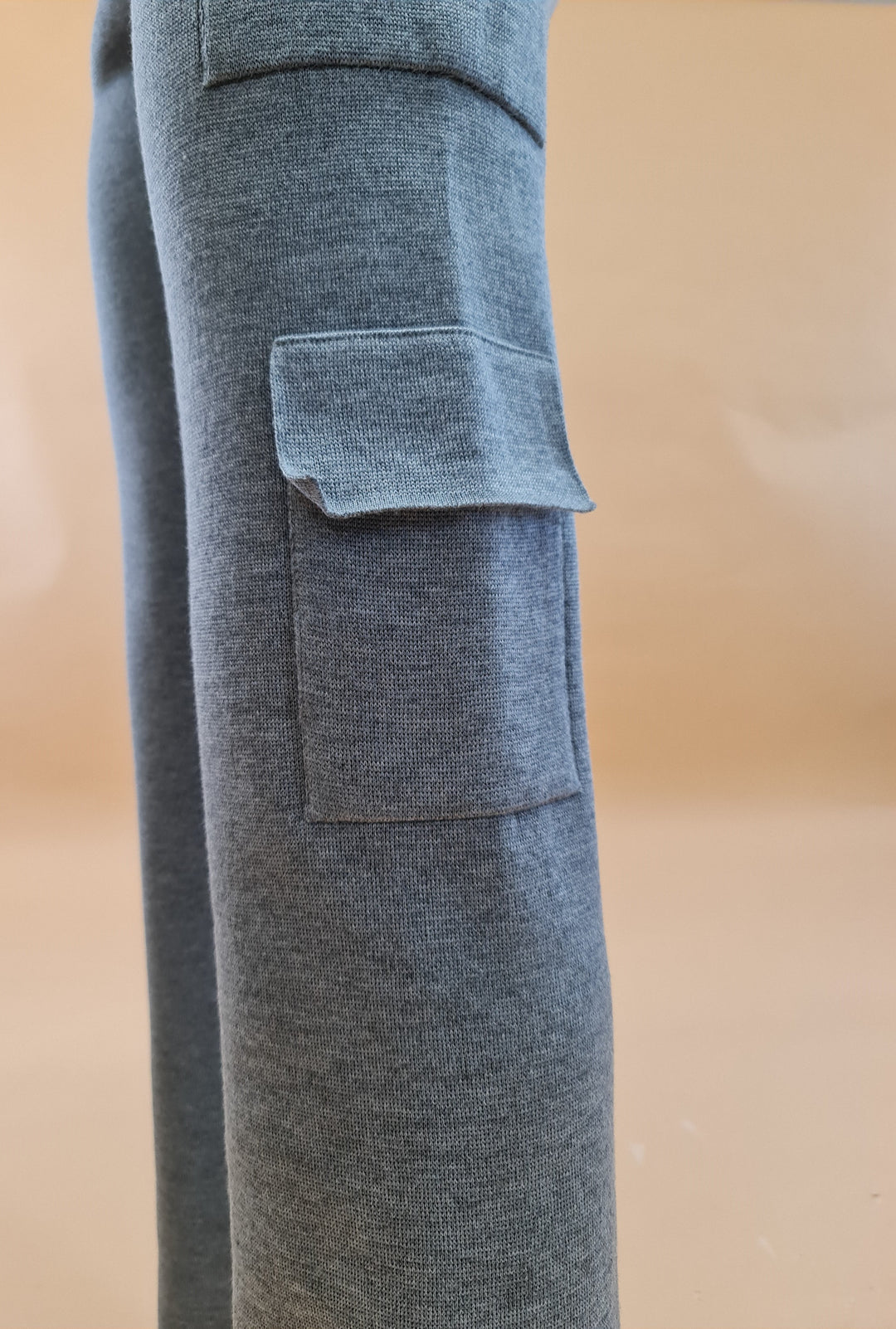 Close-up of grey jogger pants with side pocket against neutral background