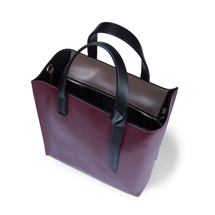 Maroon and black leather tote bag with dual handles and inner pocket