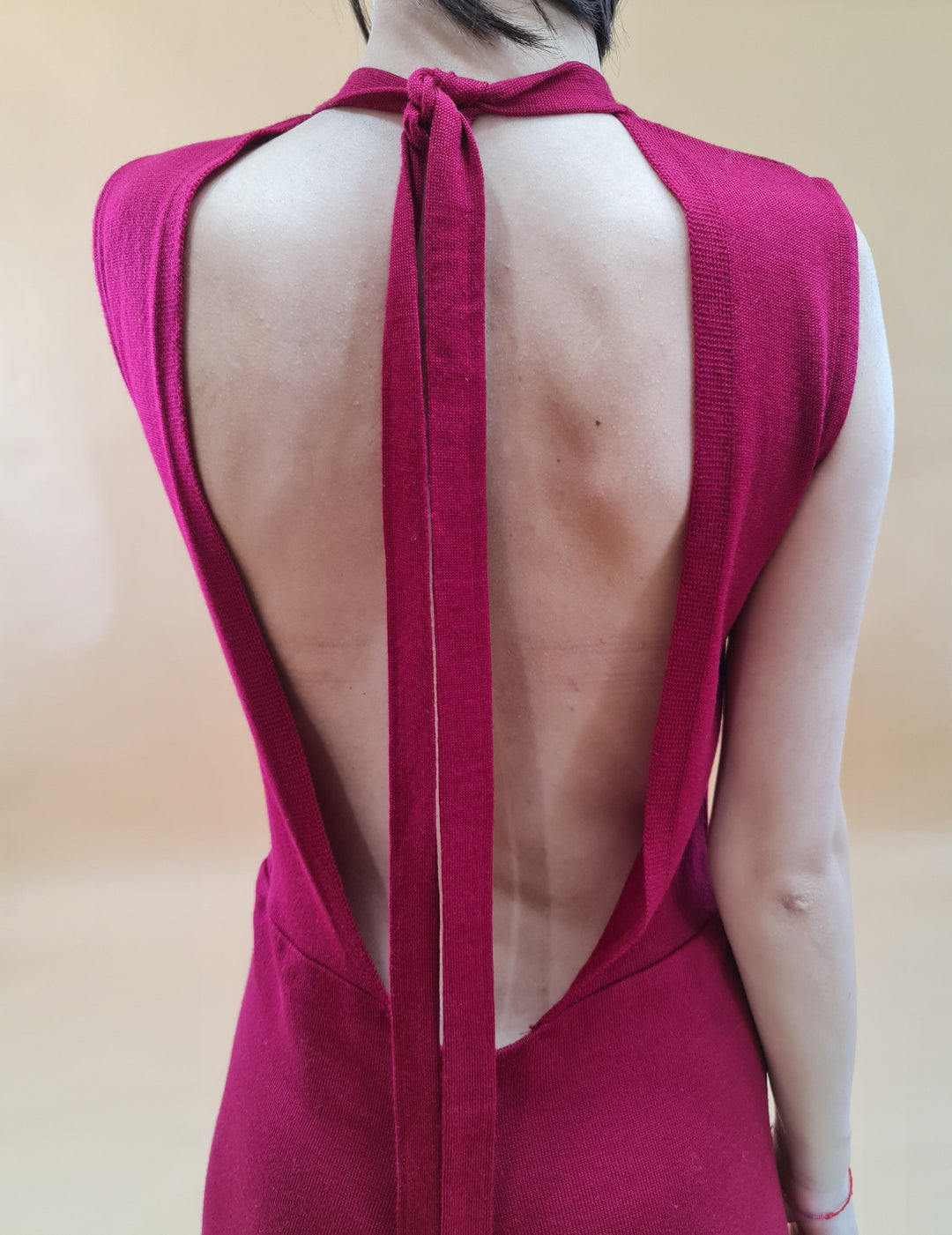 Back view of a person wearing a sleeveless backless red dress with a tie