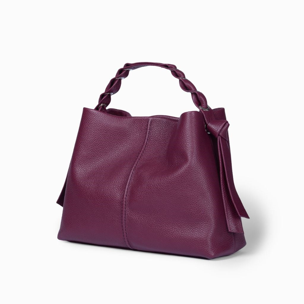 Purple leather handbag with braided handle on a white background