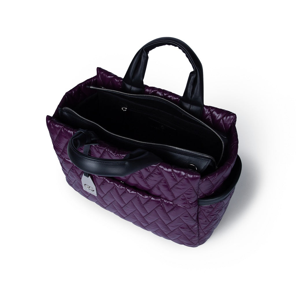 Top view of a stylish purple quilted handbag with black handles and multiple compartments