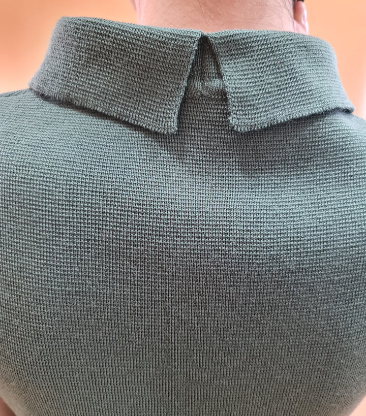 Close-up of a person wearing a green textured collared sweater