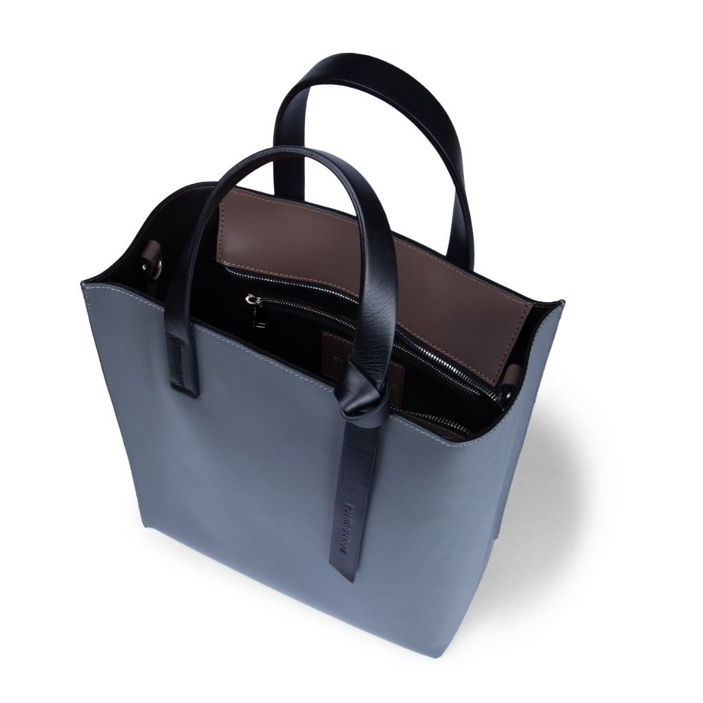 Minimalist blue leather tote bag with black handles and brown interior