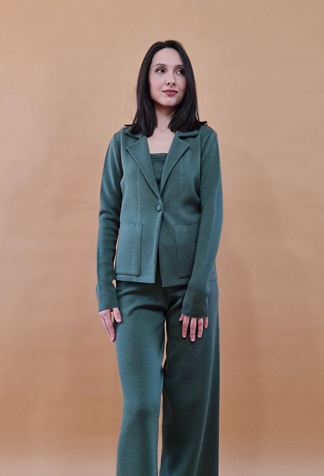 Woman wearing a green pantsuit against a beige background