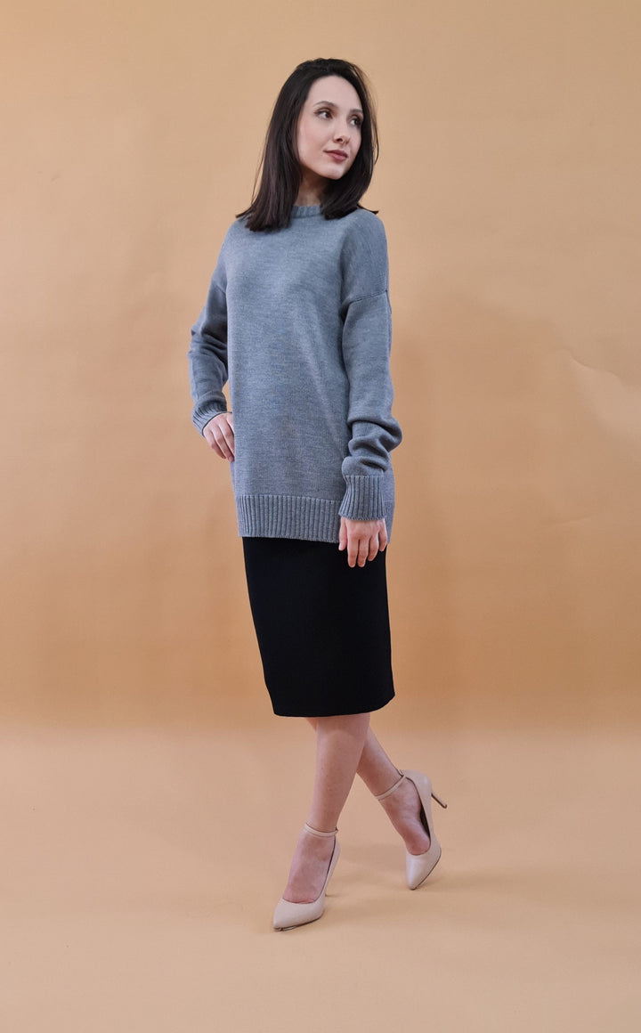 Woman posing in stylish gray sweater and black skirt outfit