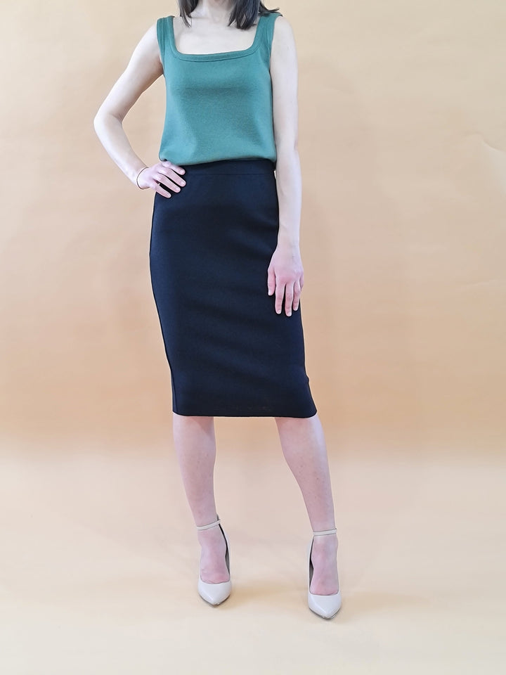 Woman wearing sleeveless green top and black pencil skirt with beige high heels