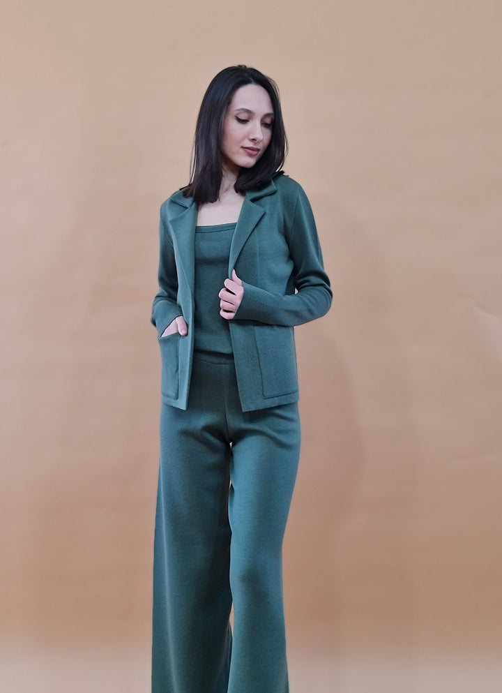 Woman wearing a stylish green pantsuit against a beige background