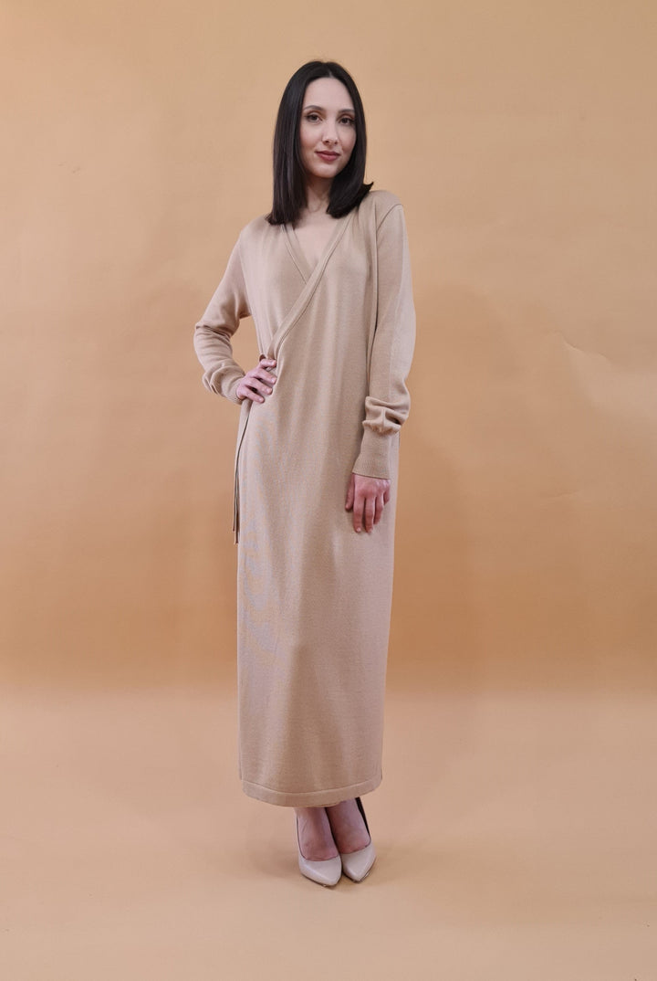 Woman in beige wrap dress posing against a warm beige background