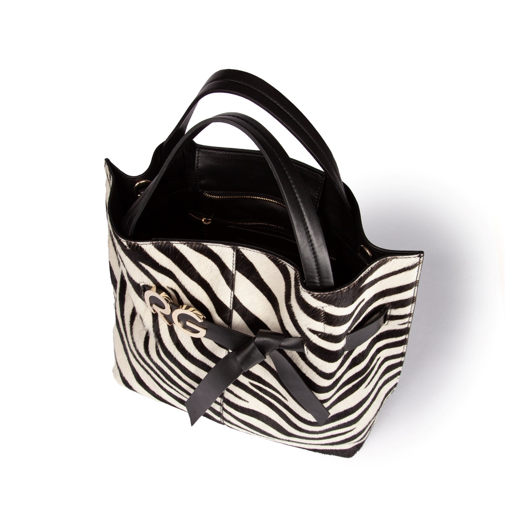 Black and white zebra print handbag with black leather handles and bow accent