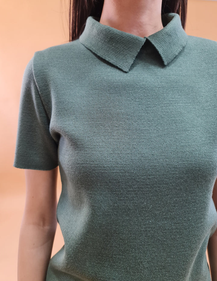 Green short-sleeve knit top with a collared neckline worn by a person