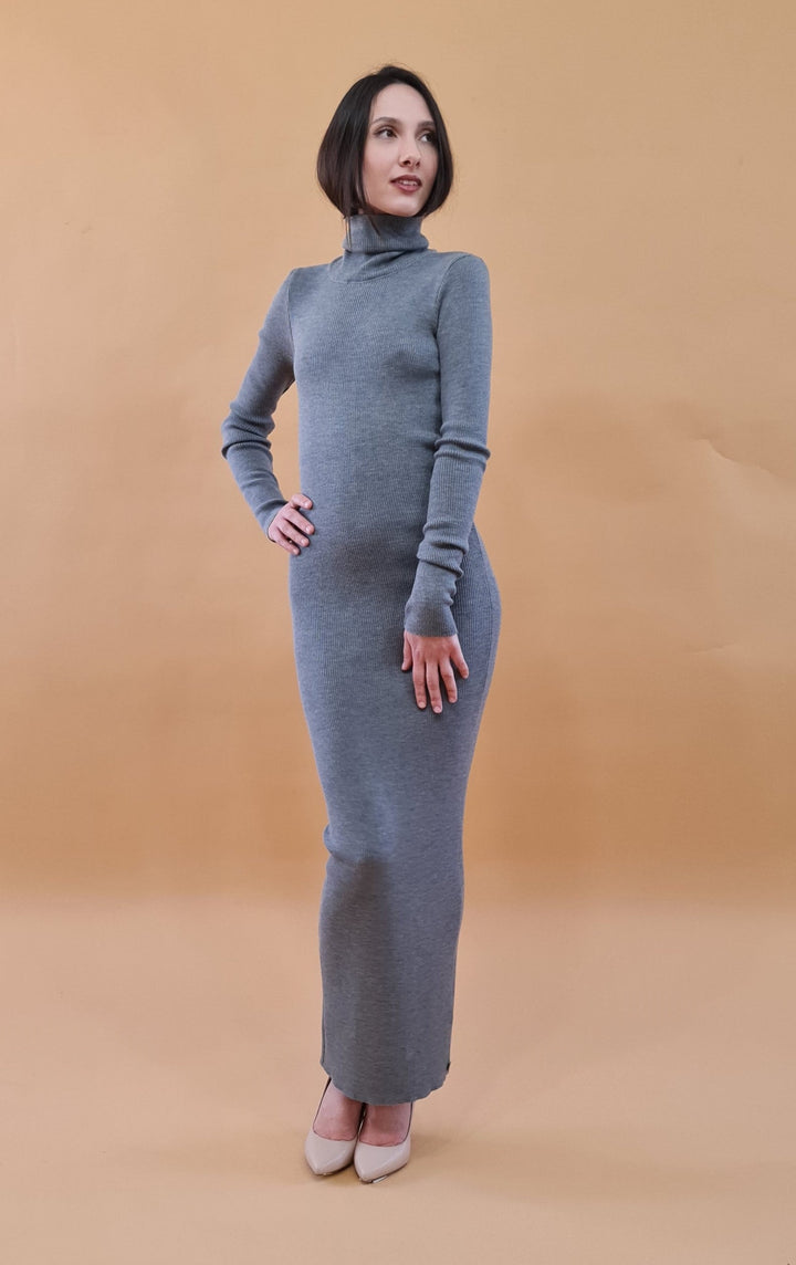 Woman in gray turtleneck dress posing against a beige background