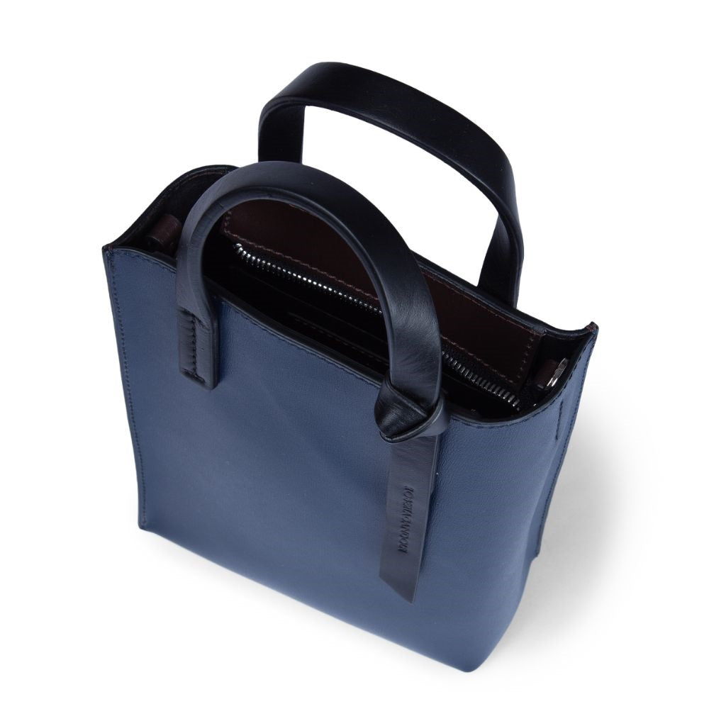 Top view of a navy blue leather handbag with a black handle and zipper compartment