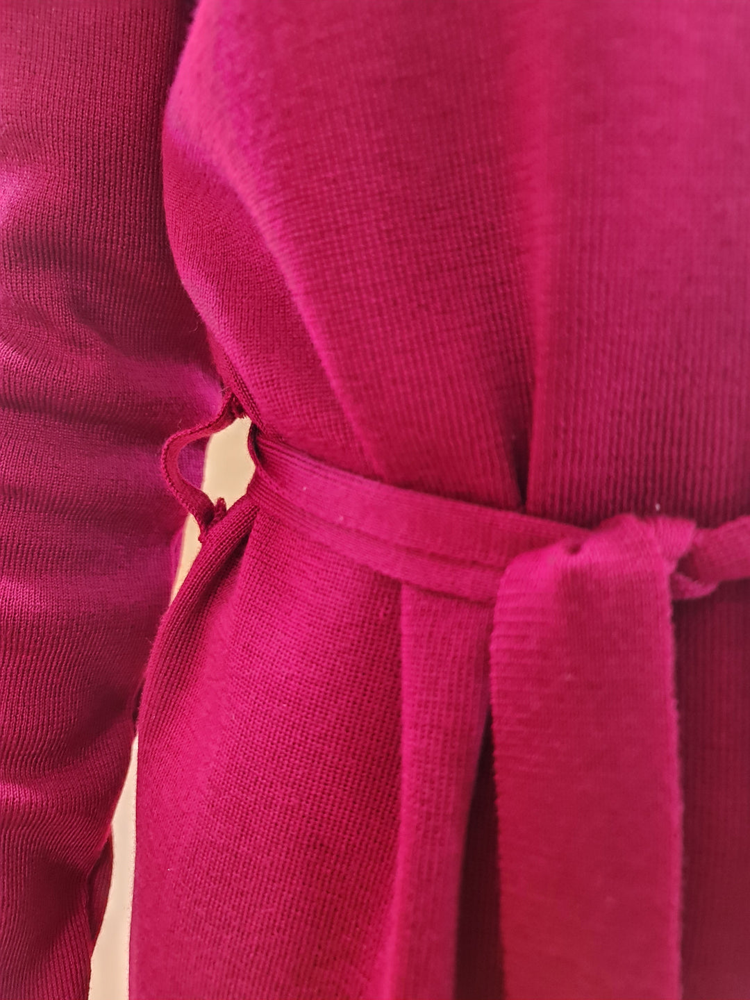 Close-up of a person wearing a red knit sweater dress with a tied belt