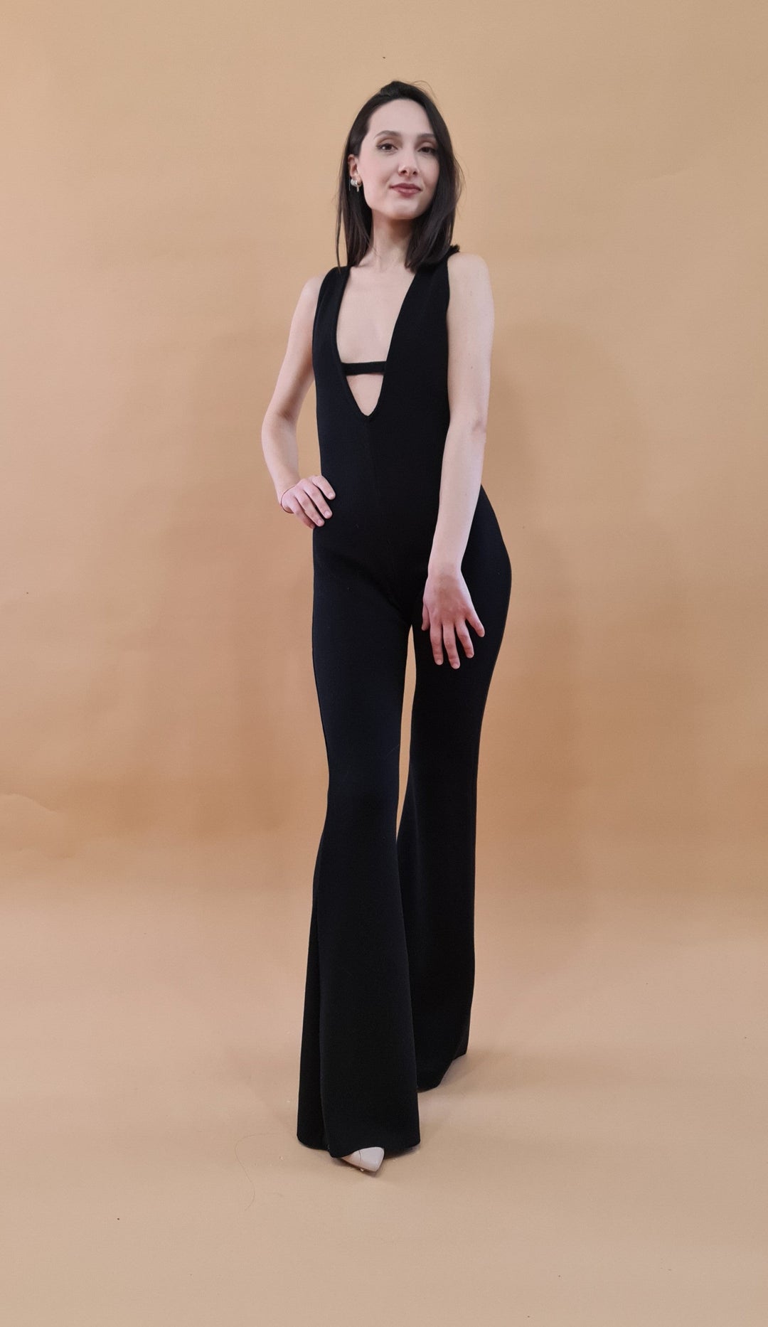 Woman in a stylish black jumpsuit posing against a plain background