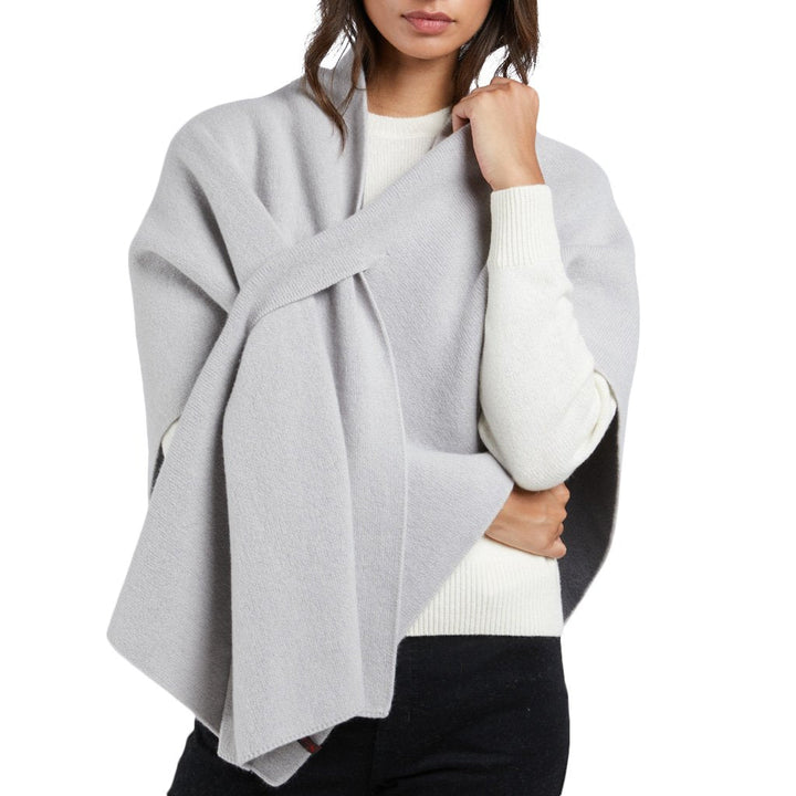 Woman wearing a light gray cashmere wrap shawl over a white sweater