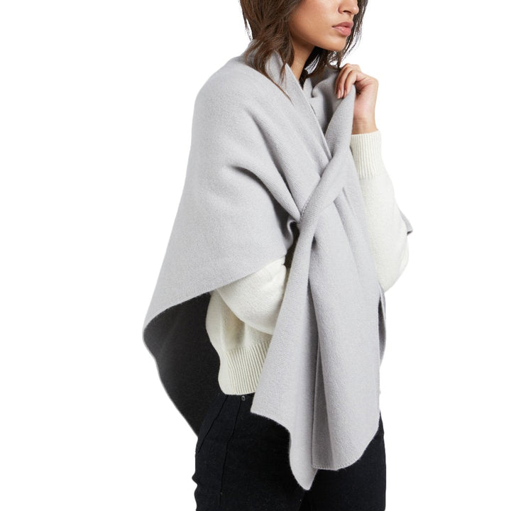 Woman wearing a cozy light gray shawl over a white sweater and black pants