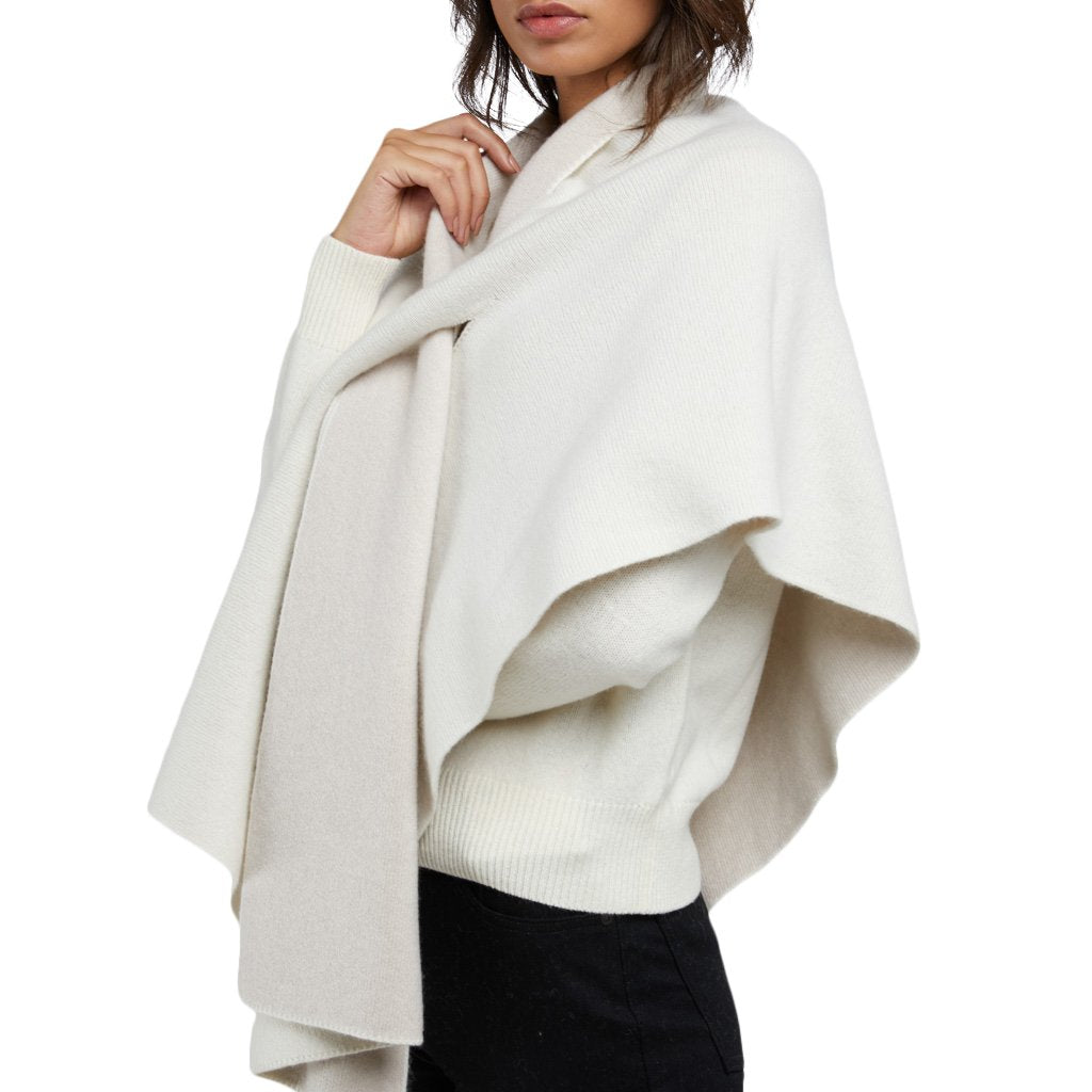 Woman wearing a stylish cream-colored shawl over a white sweater