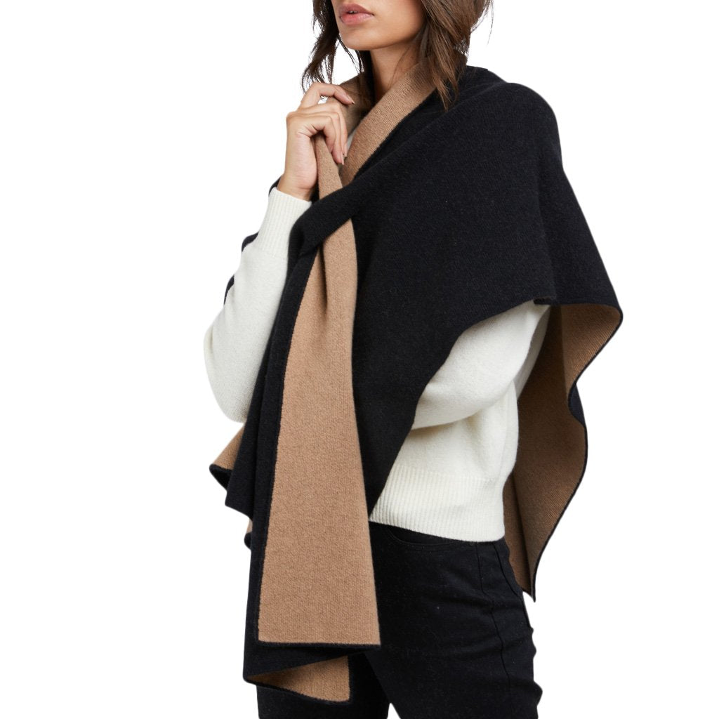 Woman wearing a stylish black and beige shawl over a white sweater