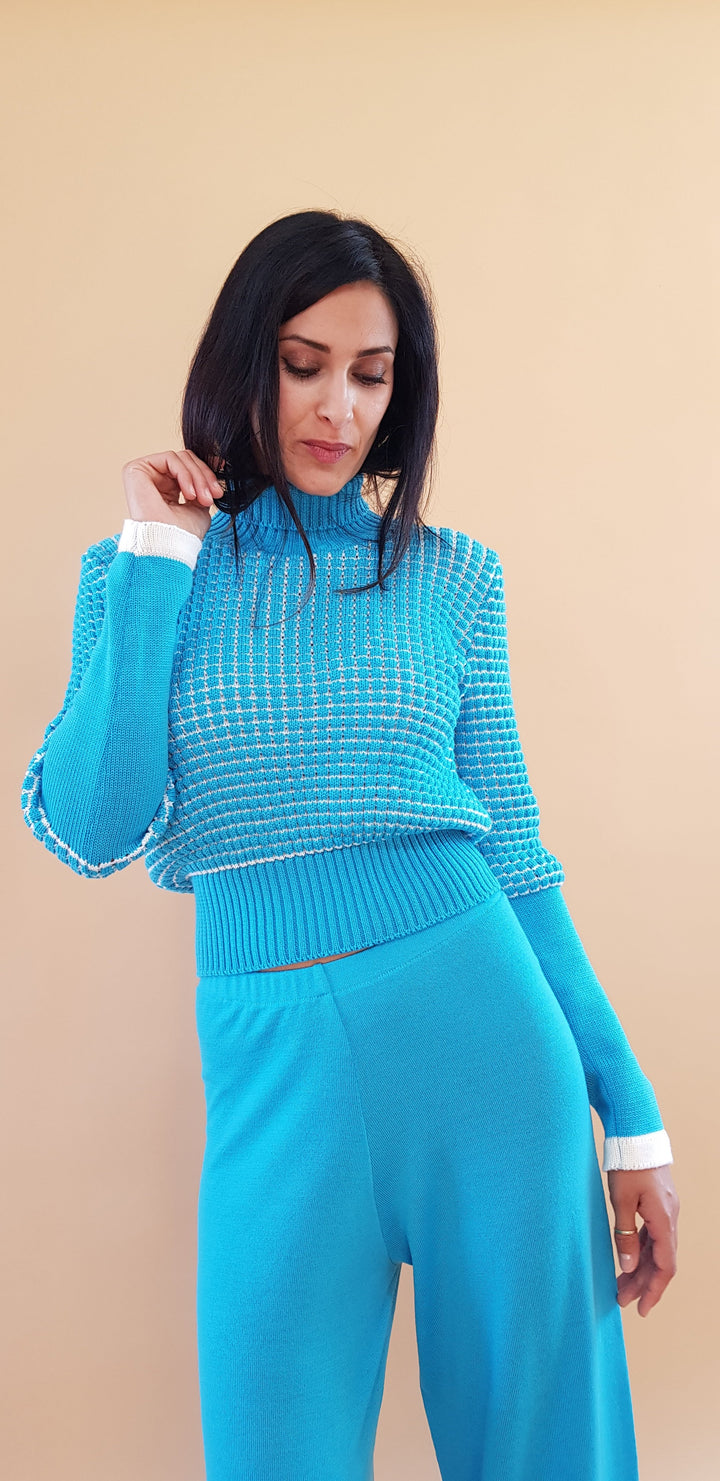 Woman wearing a blue long-sleeve sweater and matching pants against a beige background