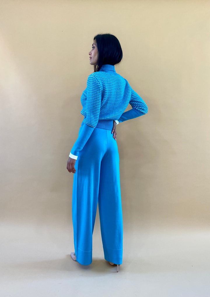 Woman in blue outfit posing against a beige background