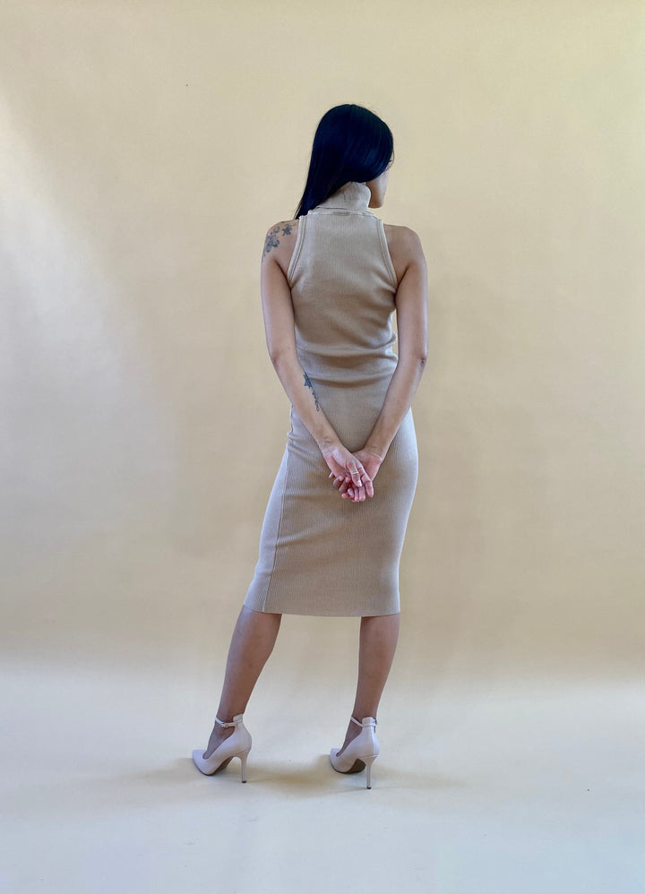 Woman in a tan sleeveless dress standing with her back to the camera