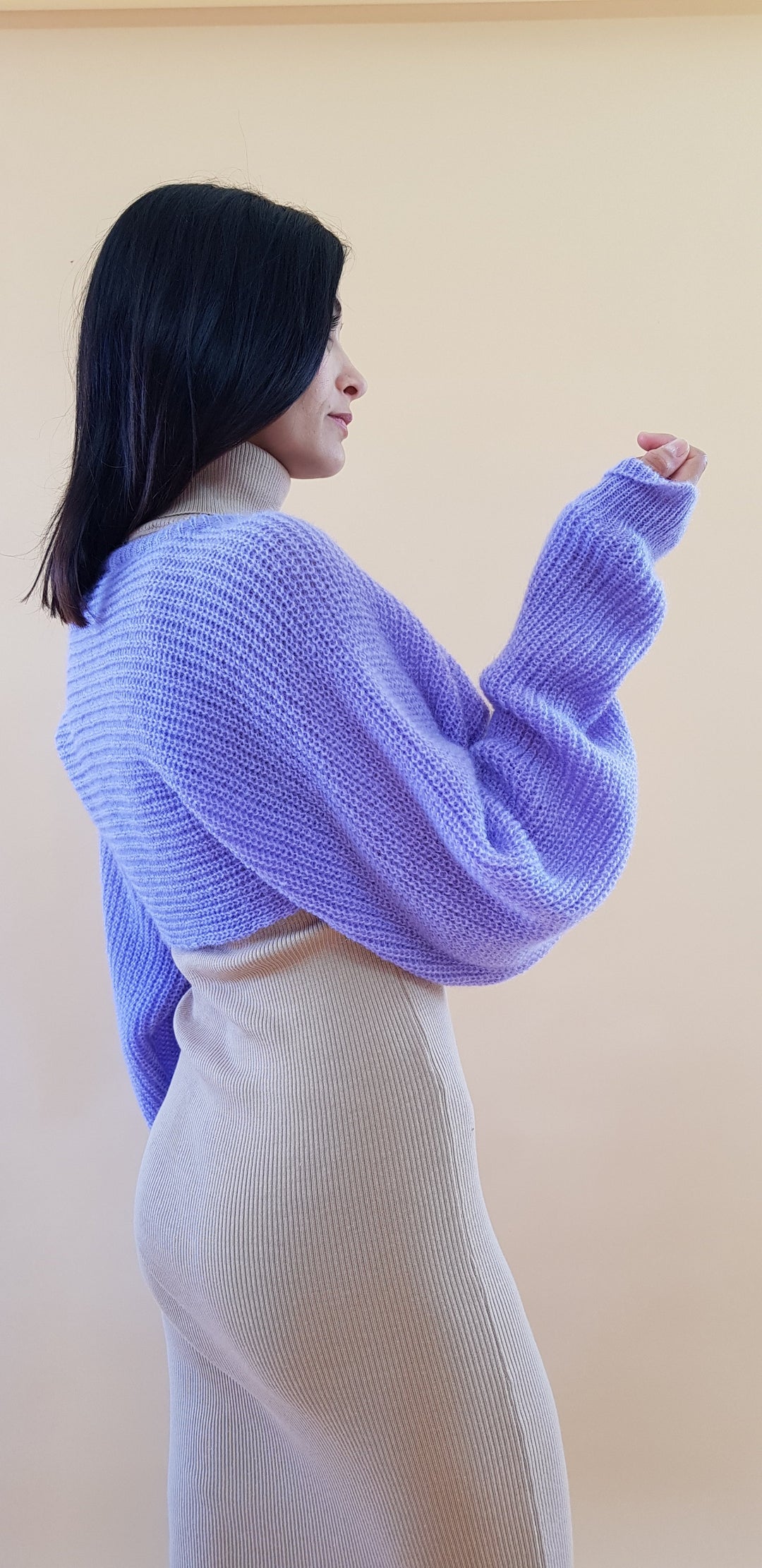 Woman posing in a light purple knitted sweater and beige ribbed skirt against a plain background