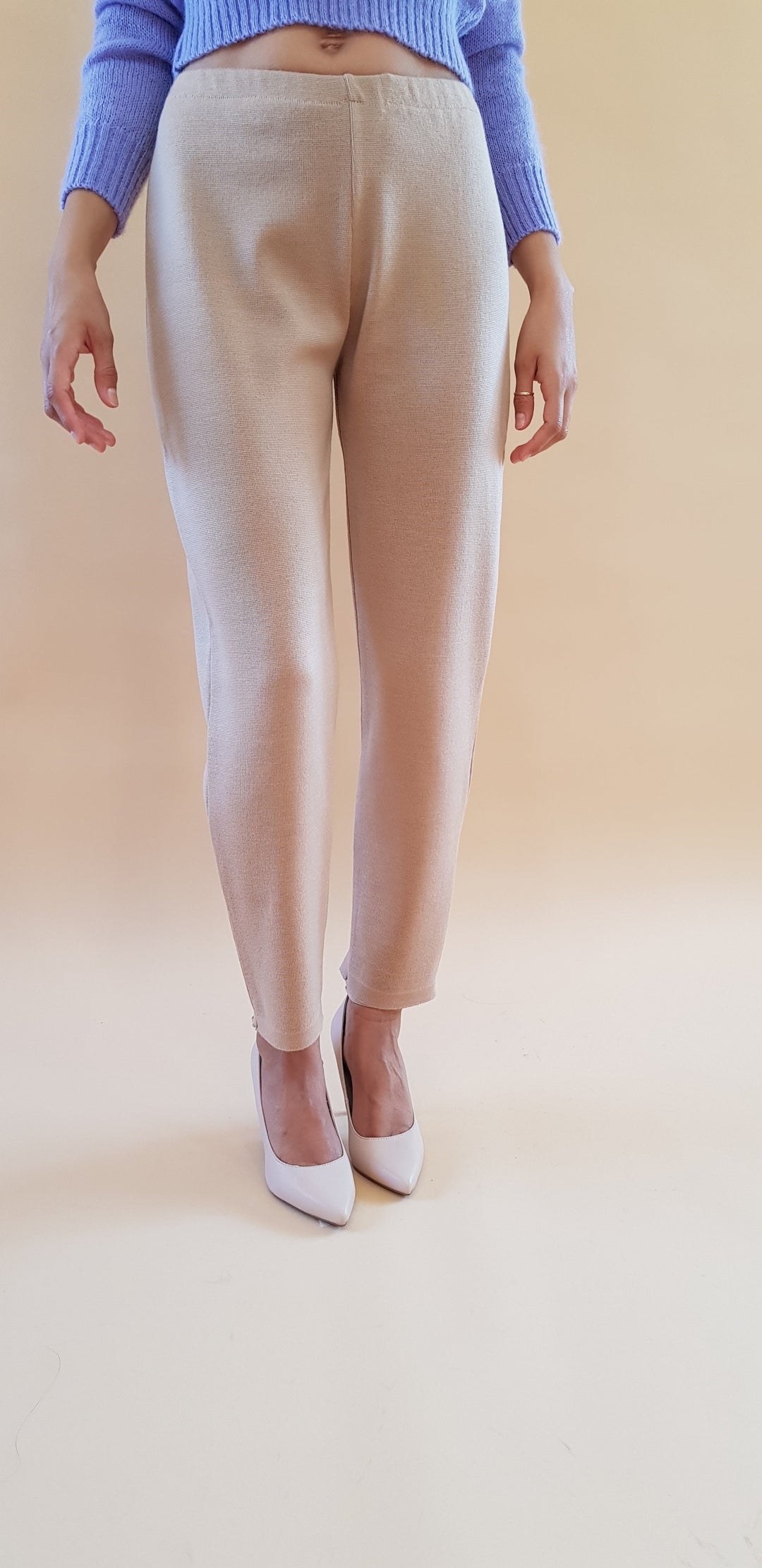 Person wearing beige pants and white shoes on a neutral background