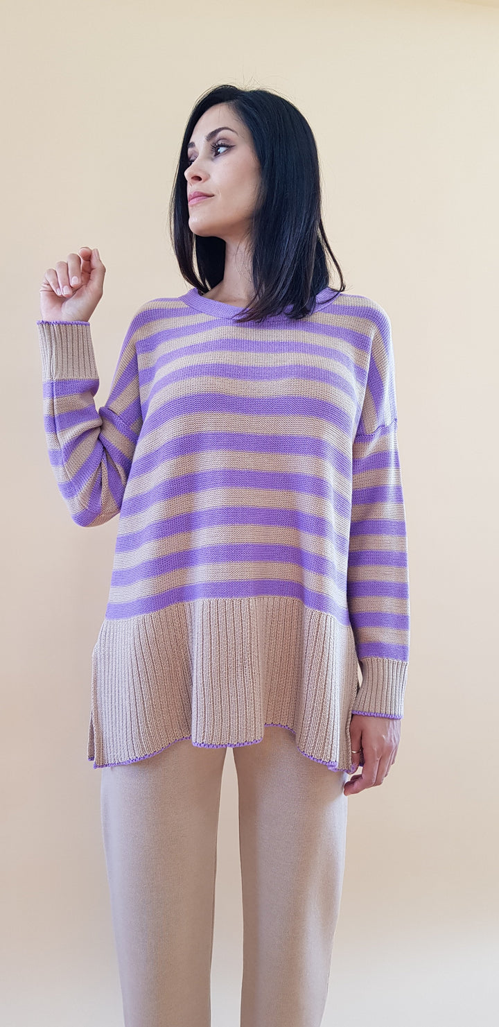 Woman in a purple and beige striped sweater against a beige background