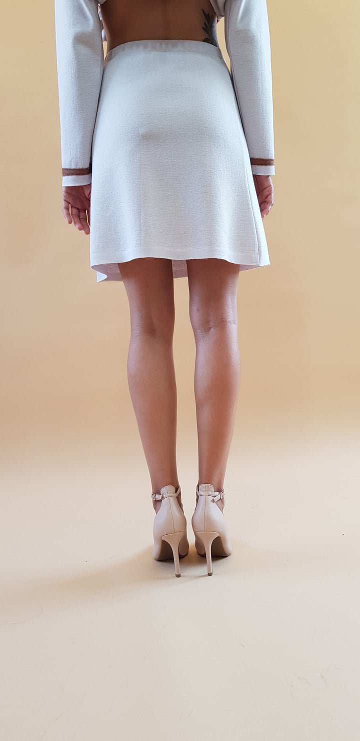 Back view of a woman wearing a white dress and beige high heels on a beige background