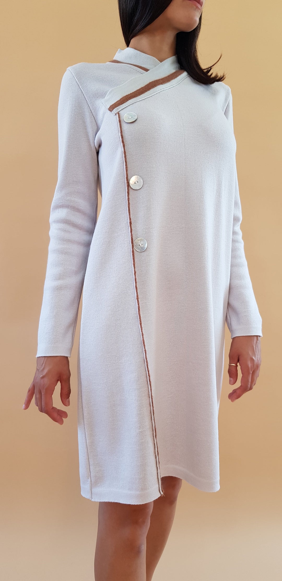 Woman in long-sleeve white dress with asymmetrical button design