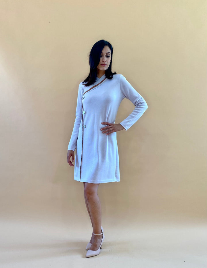 Woman wearing a white asymmetrical buttoned dress with long sleeves