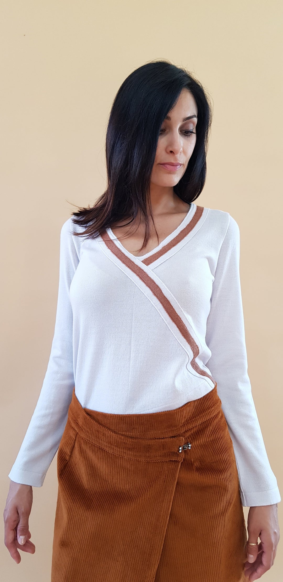 Woman wearing white wrap top with brown stripe and brown skirt