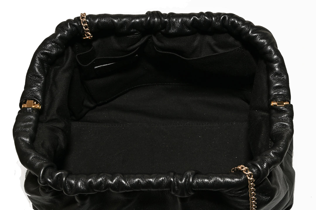 Top view of an open black leather handbag with a drawstring closure and gold chain detail