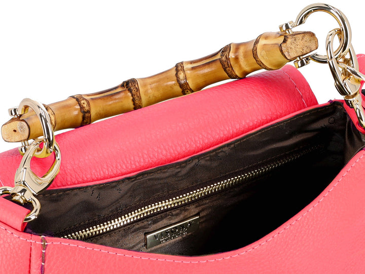 Close-up of a pink handbag with bamboo handle and gold hardware detailing