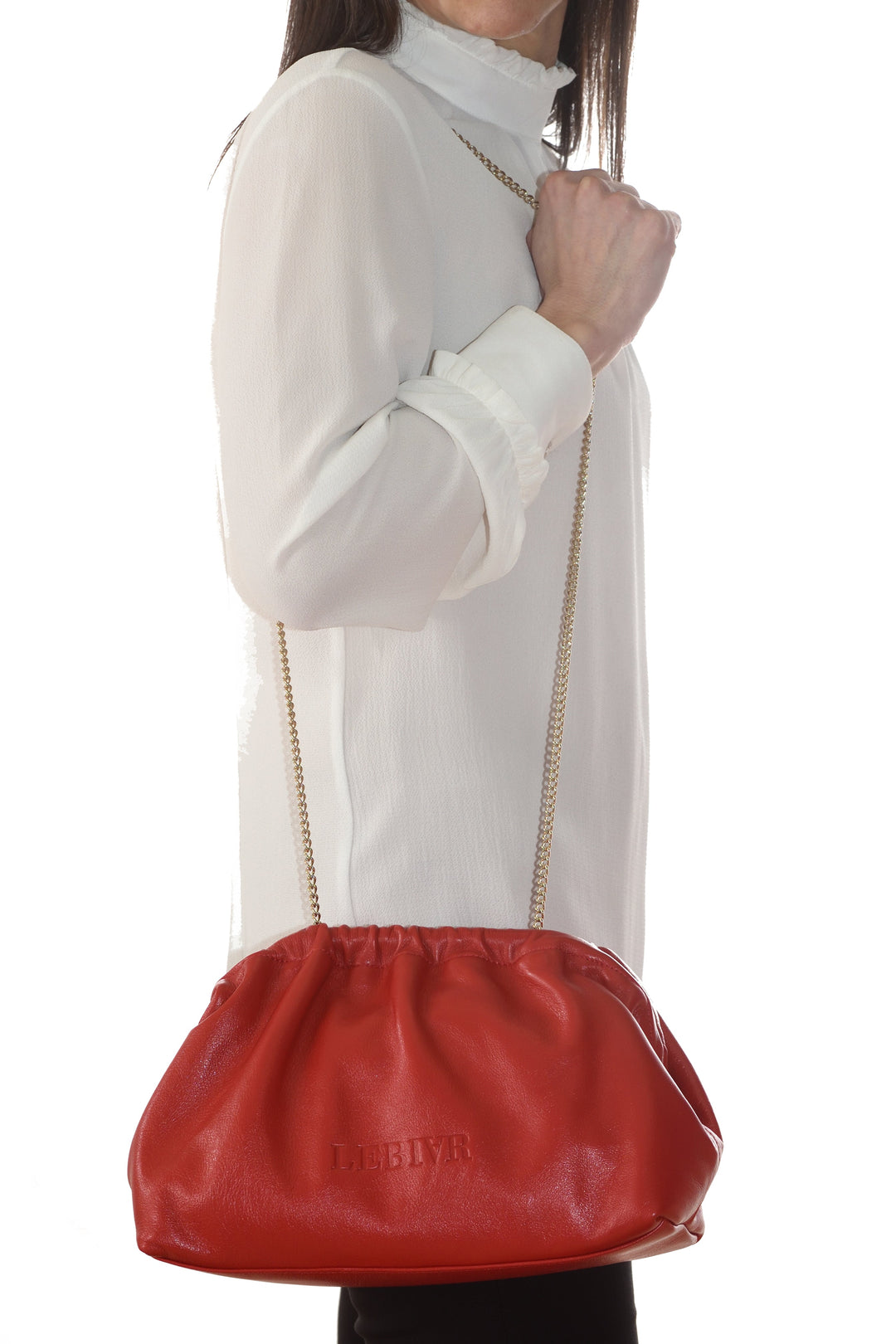 Woman holding a red leather handbag with a gold chain strap against a white background