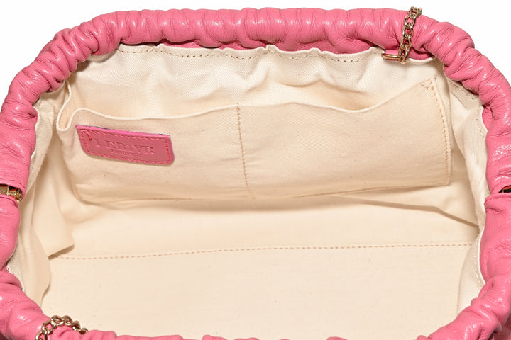 Interior view of a pink leather handbag with beige fabric lining and pockets
