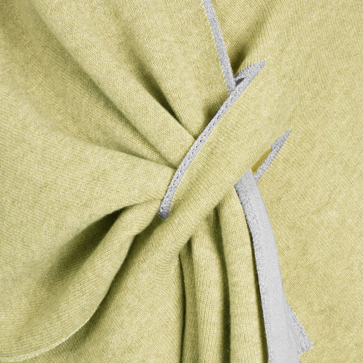 Close-up of light green fabric with intricate fold and seam details