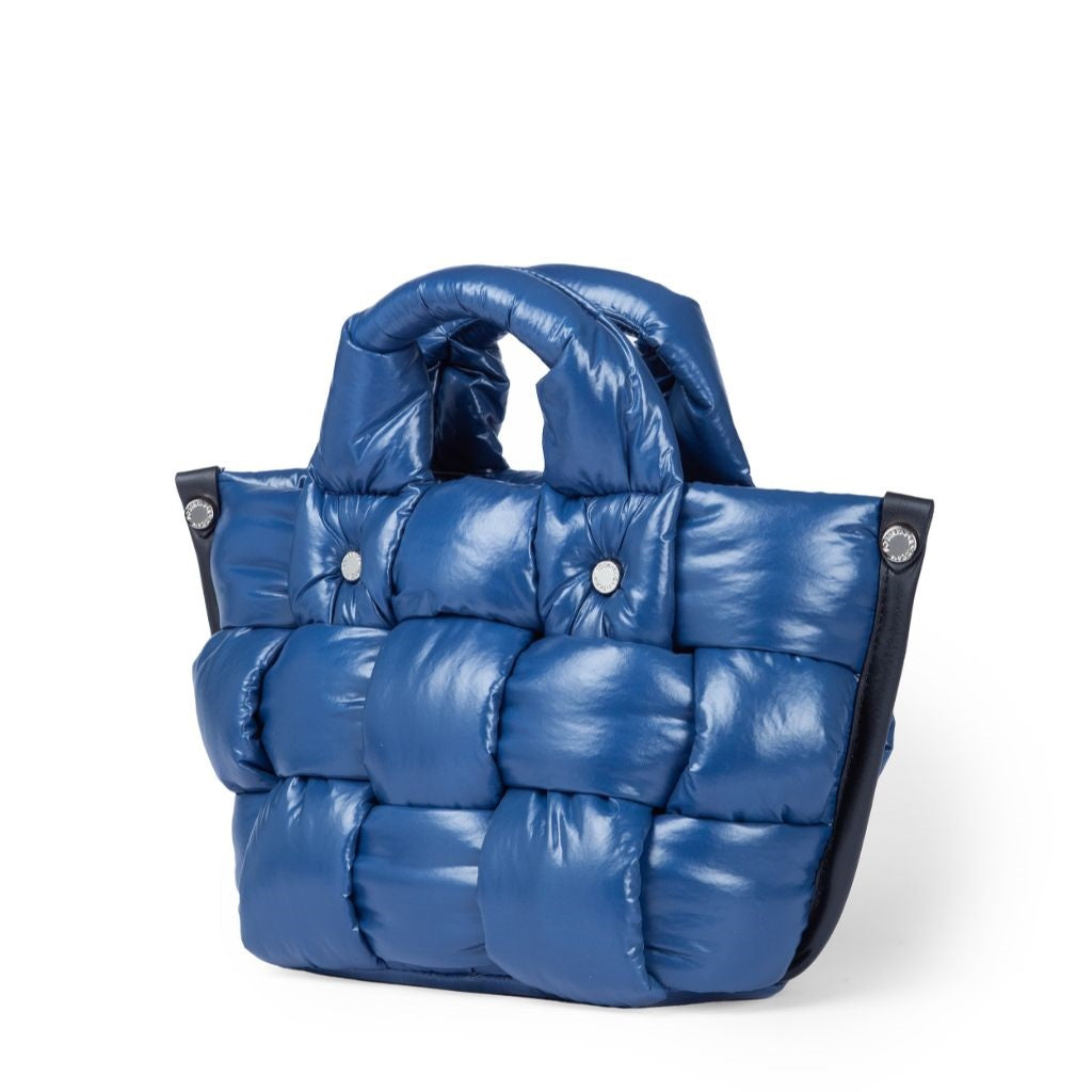 Blue quilted puffer tote bag with snap button details on a white background