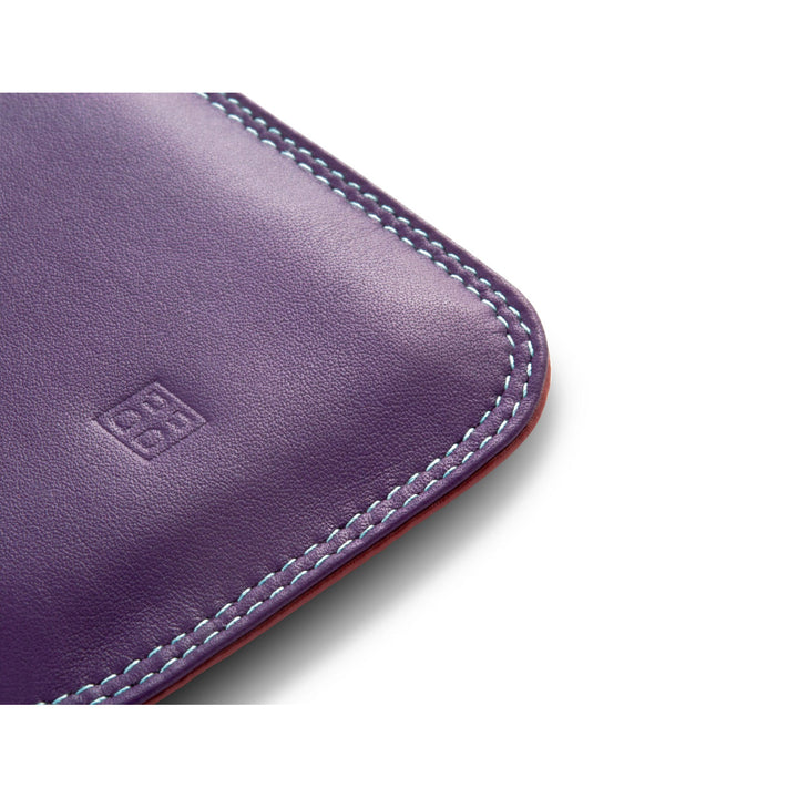 Close-up of a purple leather wallet corner with detailed stitching and embossed logo