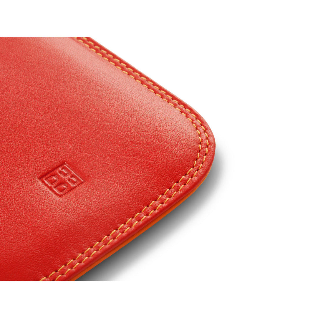 Close-up of red leather notebook cover with embossed logo and detailed stitching