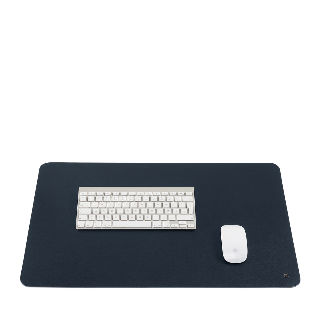 Minimalist workstation with white keyboard and mouse on dark desk mat