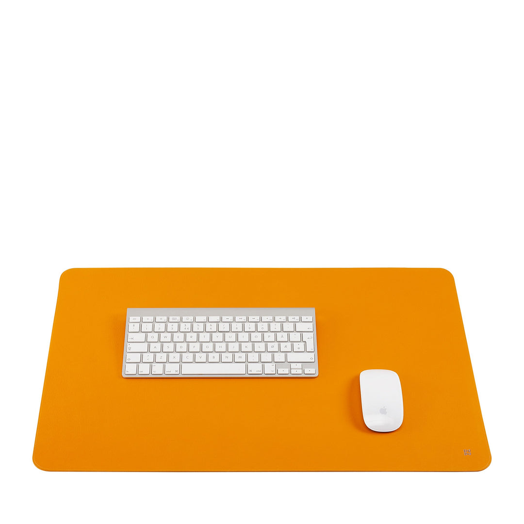 Minimalist workspace with orange desk pad, wireless keyboard, and mouse